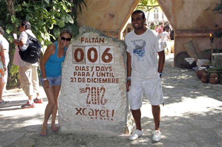 Tourists get their picture taken next to a slab of stone counting down the days until Dec. 21, 2012 at the Xcaret theme park in Playa del Carmen, Mexico, Saturday, Dec. 15, 2012. Amid a worldwide frenzy of advertisers and new-agers preparing for a Maya apocalypse, one group is approaching Dec. 21 with calm and equanimity calm: the people whose ancestors supposedly made the prediction in the first place. Mexico's 800,000 Mayas are not the sinister, secretive, apocalypse-obsessed race they've been made out to be.  (AP Photo/Israel Leal)
